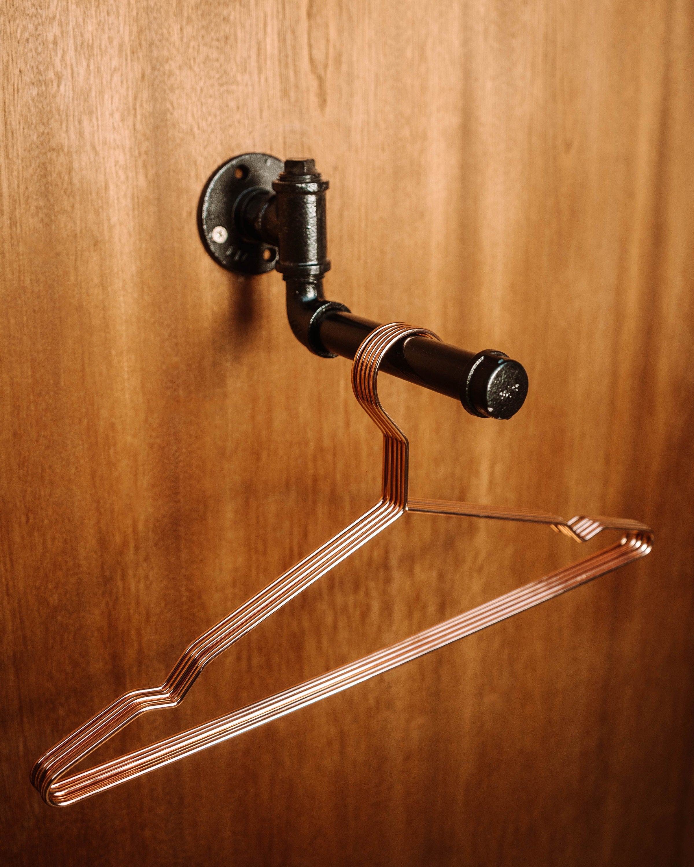 A modern Clothes Rail Wall Mount with hanging garments, offering a space-efficient and stylish way to organize clothing.