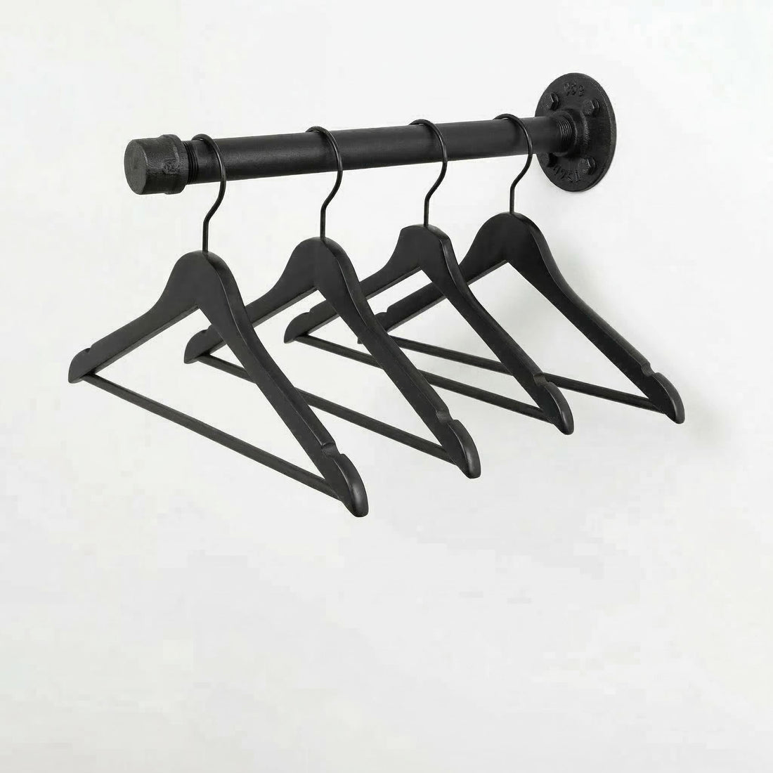A black metal hanger rack with four black wooden hangers hanging from it.