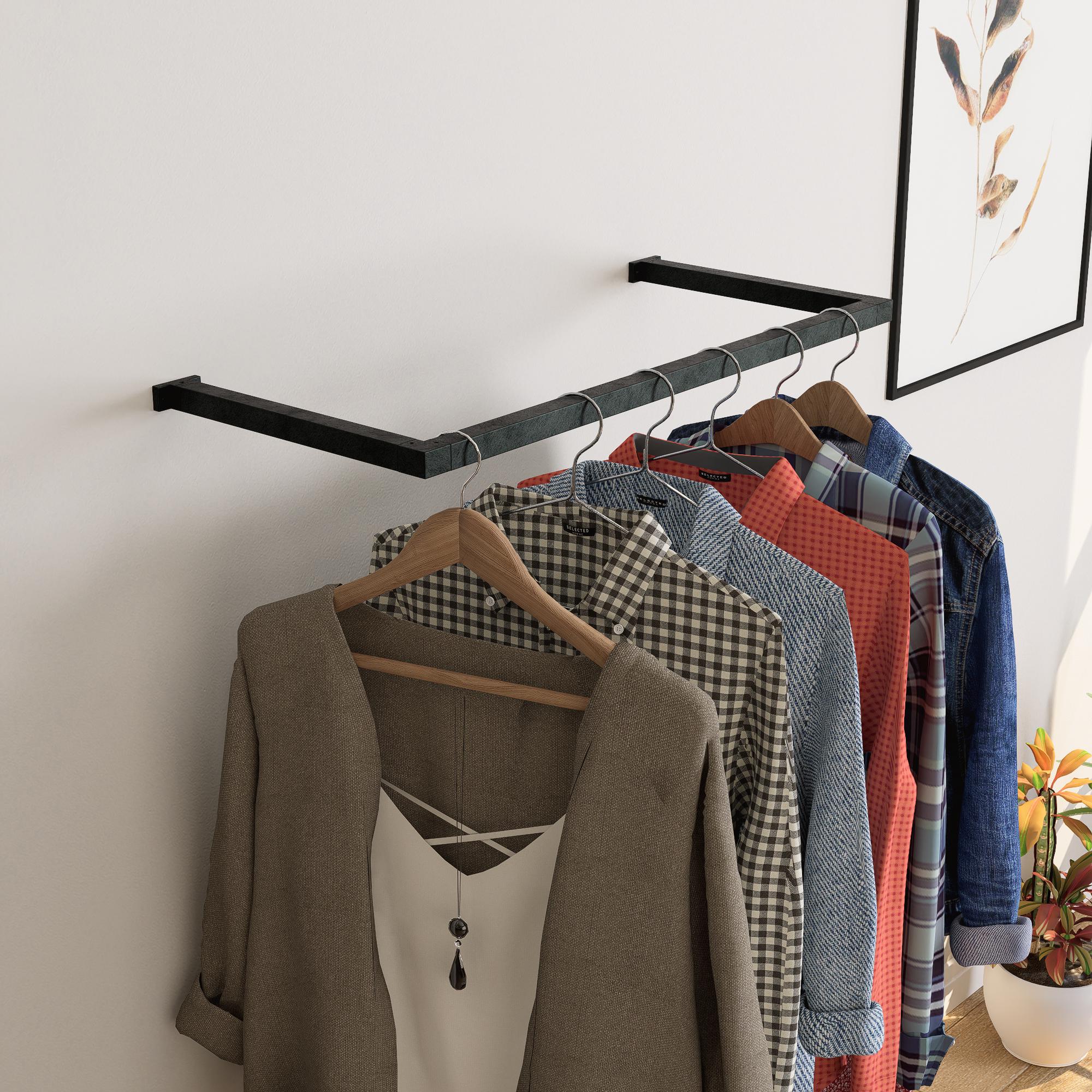 wall-mounted clothing rack with wooden hangers holding shirts and jackets, placed against a neutral wall with minimal decor.