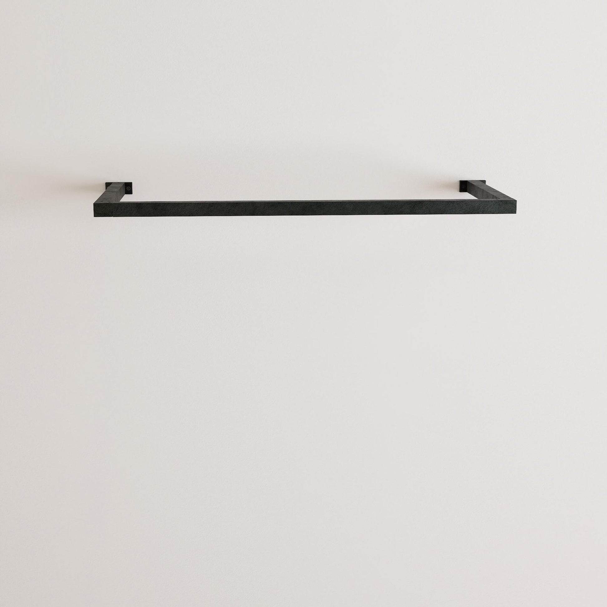 wall-mounted clothing rack with wooden hangers holding shirts and jackets, placed against a neutral wall with minimal decor.