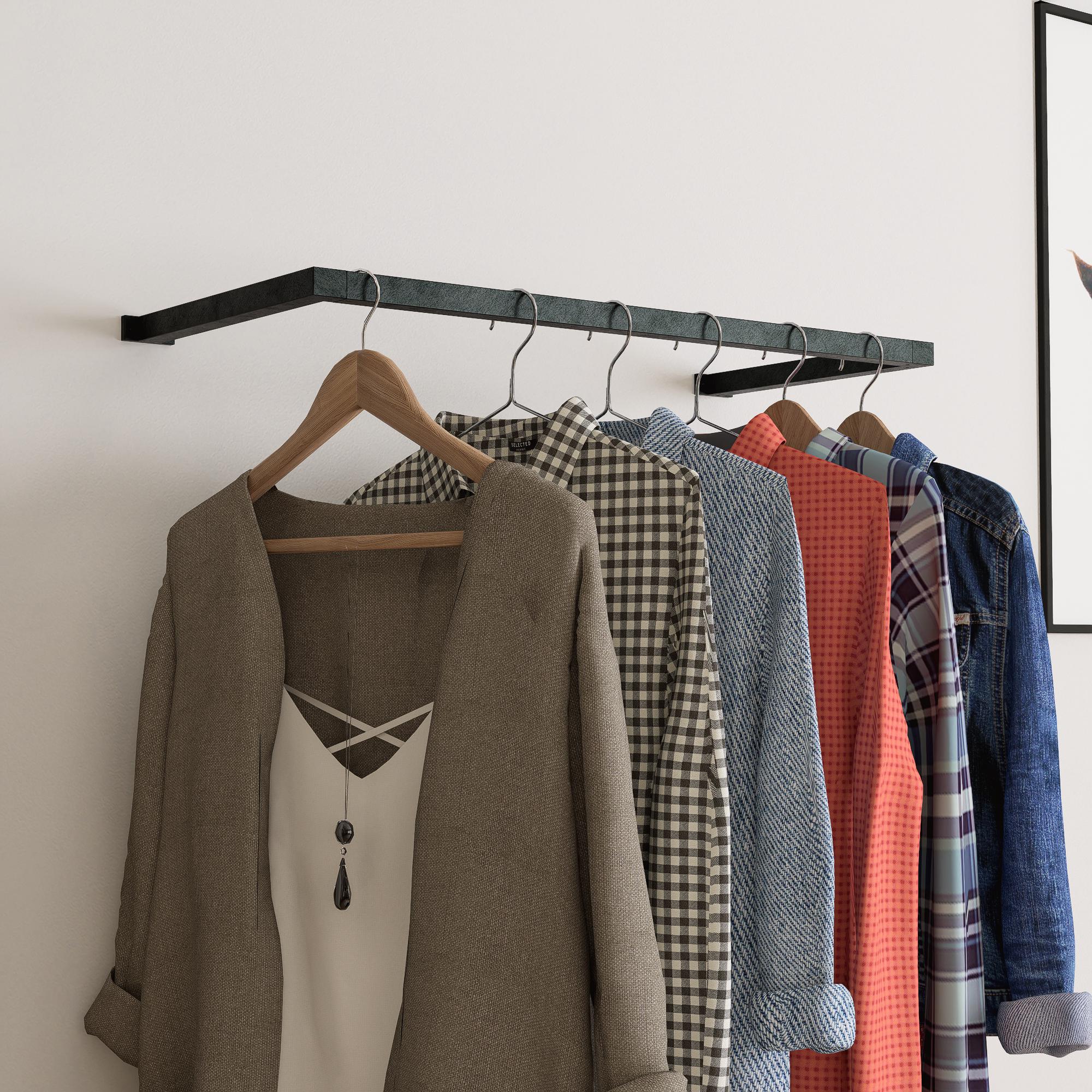 wall-mounted clothing rack with wooden hangers holding shirts and jackets, placed against a neutral wall with minimal decor.