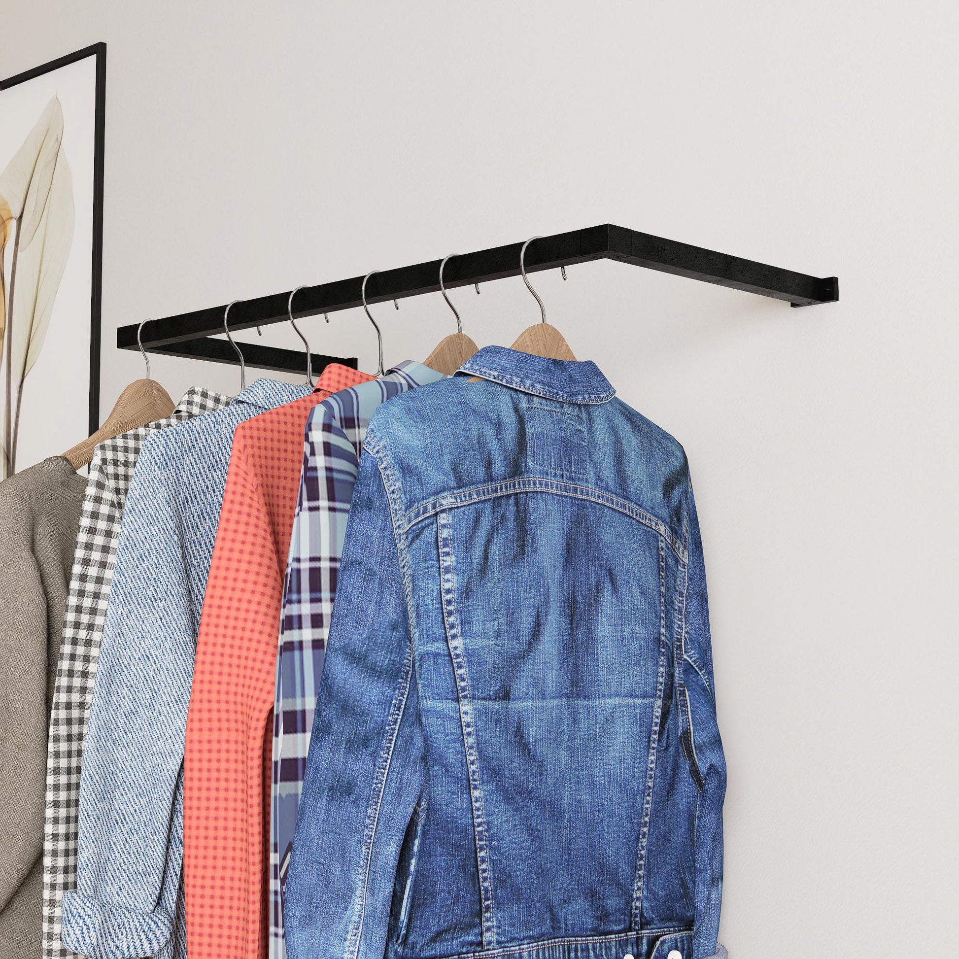 wall-mounted clothing rack with wooden hangers holding shirts and jackets, placed against a neutral wall with minimal decor.