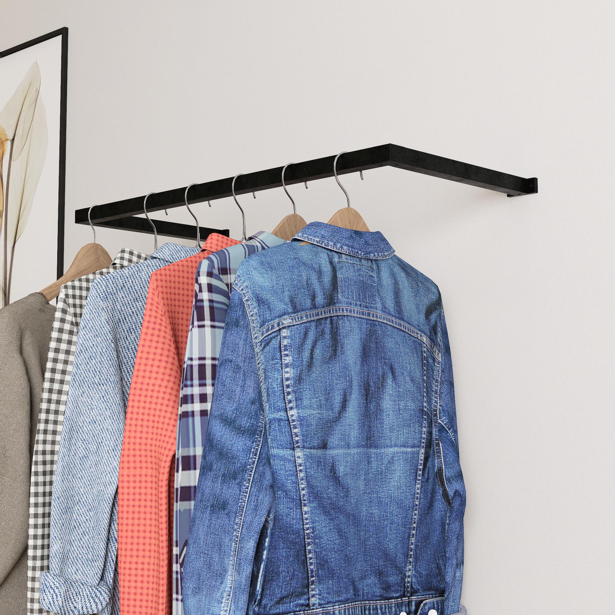 wall-mounted clothing rack with wooden hangers holding shirts and jackets, placed against a neutral wall with minimal decor.