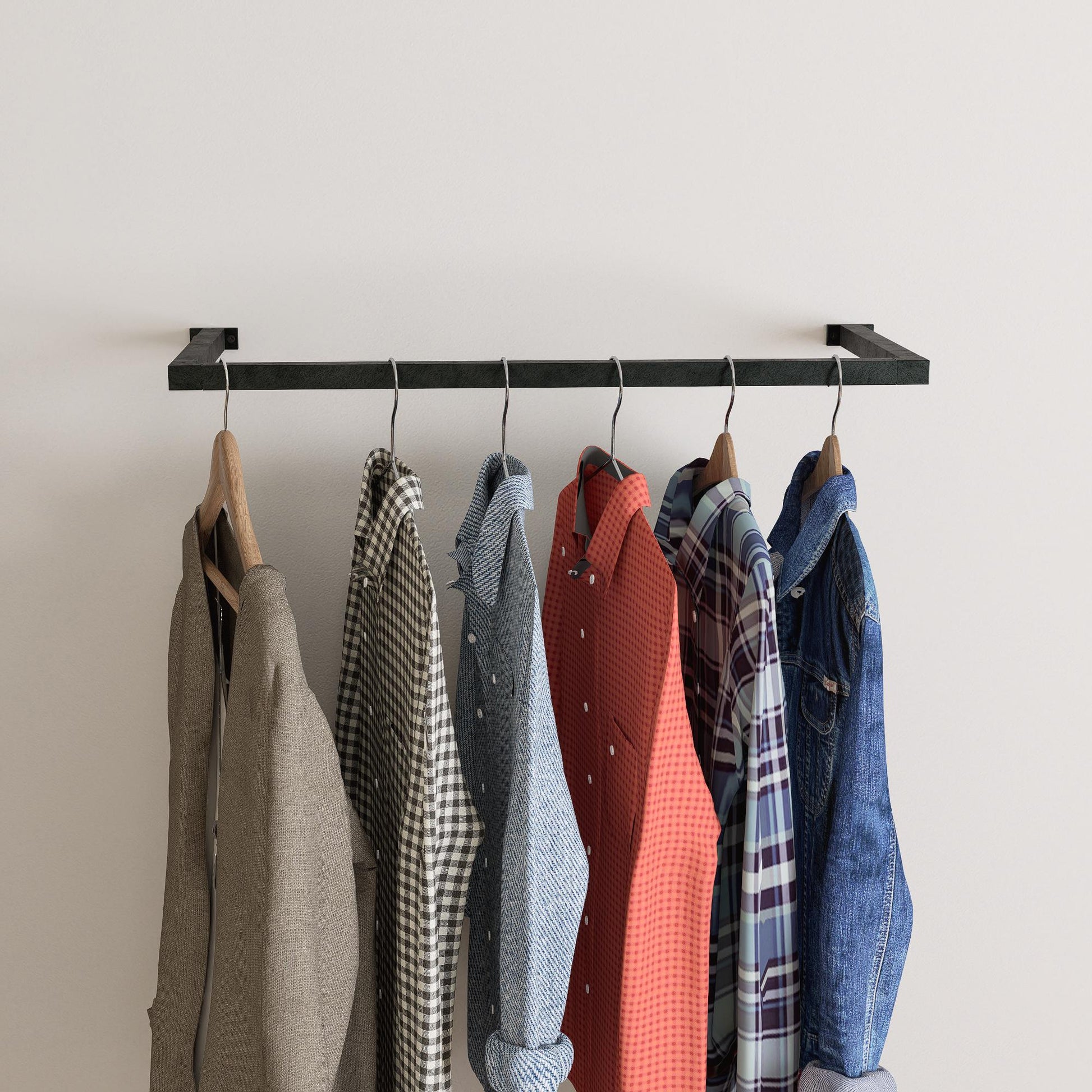 wall-mounted clothing rack with wooden hangers holding shirts and jackets, placed against a neutral wall with minimal decor.