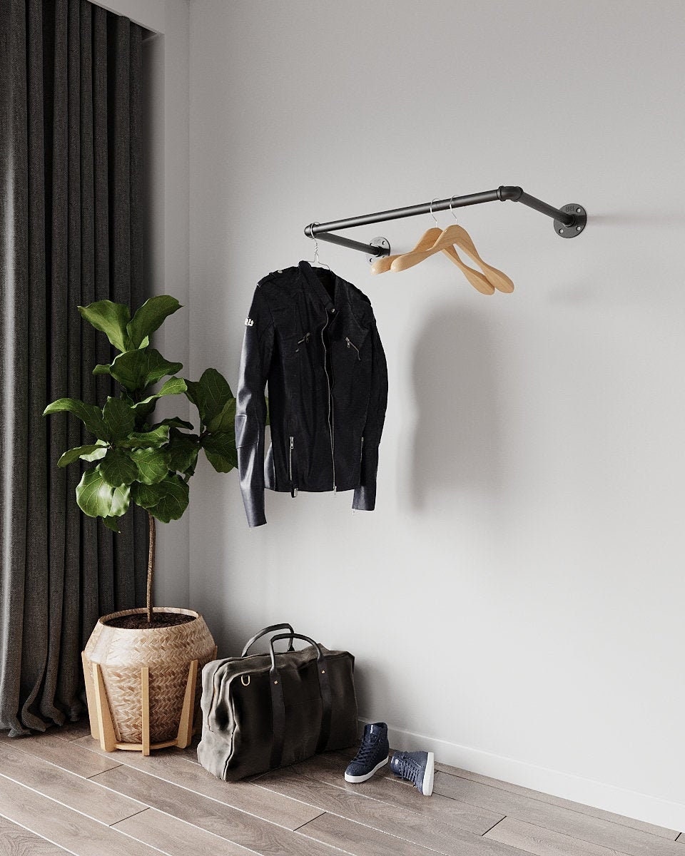 Clothes hanging on a wall-mounted pipe rack.