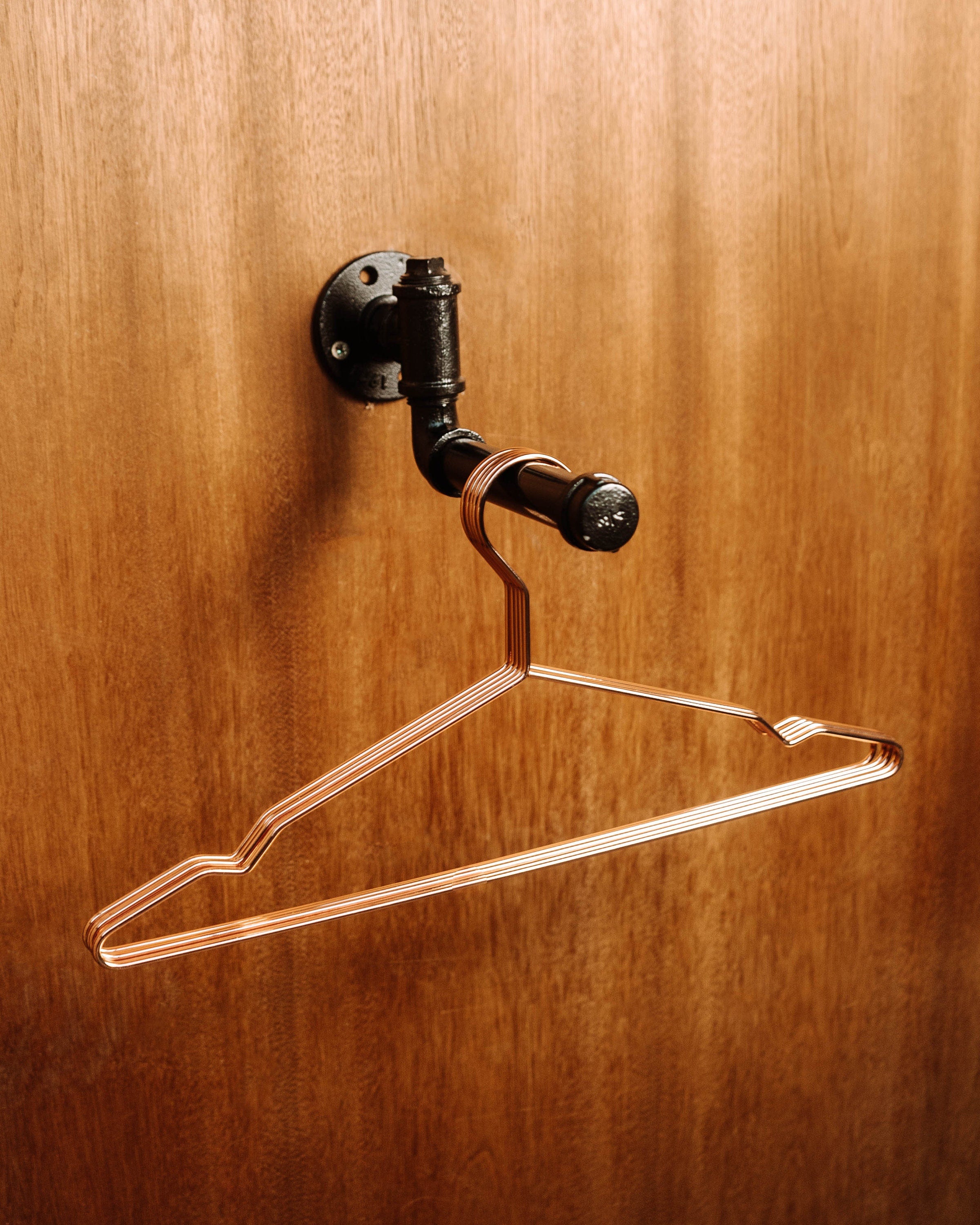 A modern Clothes Rail Wall Mount with hanging garments, offering a space-efficient and stylish way to organize clothing.